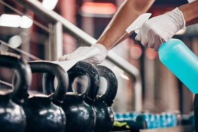 A person cleaning and disinfecting a kettlebell